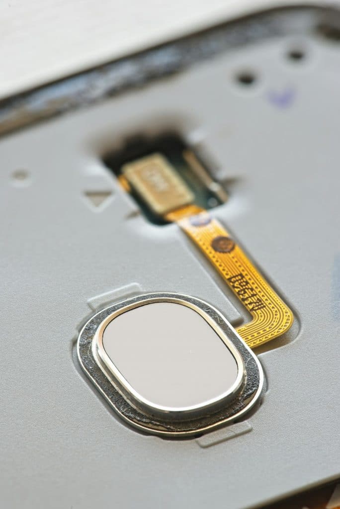 Macro detail of fingerprint scanner on smartphone with exposed electronic wires.